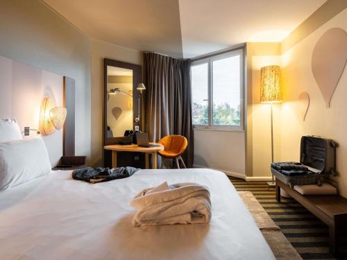 a hotel room with a bed with a towel on it at Mercure Grenoble Meylan in Meylan