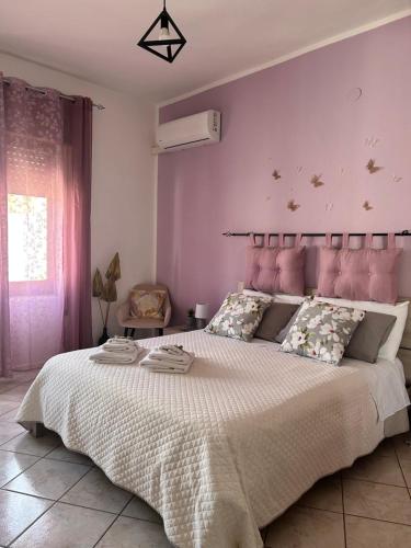 a bedroom with a large bed with a pink headboard at Butterfly House in Villaputzu