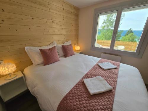 a bedroom with a large bed with a window at Les Reflets Verts - Lac de Vouglans in Maisod
