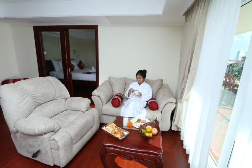 a woman sitting on a couch in a living room at Phasouk Vien Chantra Hotel in Vientiane