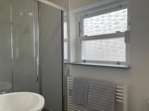 a bathroom with a shower and a sink and a window at Sea Scape in Whitstable