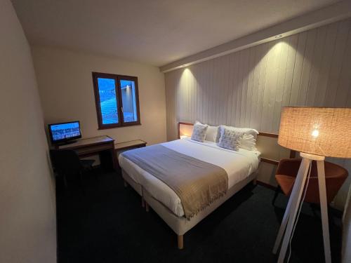 a hotel room with a bed and a desk at Hôtellerie du Roy - Restaurant Chez Robin in Sainte-Hélène-sur-Isère