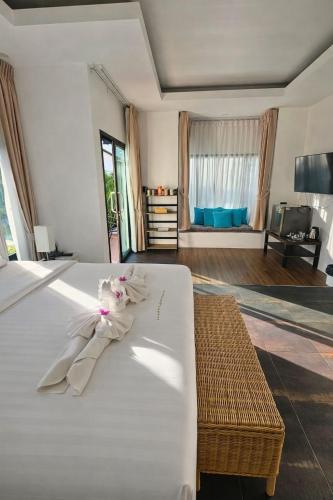 a bedroom with a white bed with a dress on it at La Casa Bangtao Resort in Ban Thalat Choeng Thale
