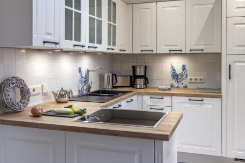 a kitchen with white cabinets and a sink at Commandeur-Huus Wohnung 1 in Borkum