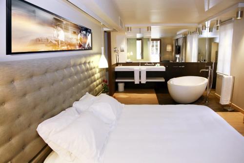 a hotel room with a bed and a bathroom at Le Pré du Moulin - Maison Alonso - Hôtel & Restaurant in Sérignan-du-Comtat