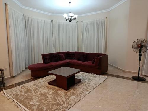 a living room with a red couch and a table at Stand alone Villa at Blumar North coast -SIDI ABD ALRAHMAN in El Alamein