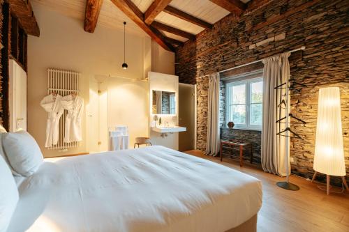 a bedroom with a large white bed and a brick wall at Château du Pont d'Oye in Habay-la-Neuve