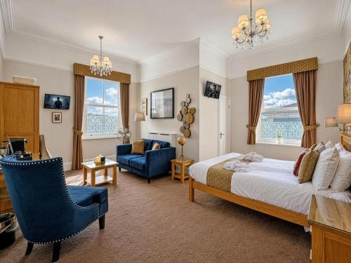 a bedroom with a large bed and a blue chair at Riviera Lodge Hotel in Torquay