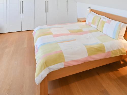 a bed with a colorful blanket on it in a room at The Longhouse At Threave in Castle Douglas