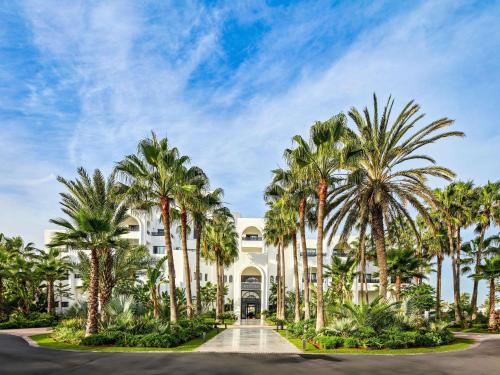a row of palm trees in front of a building at Pullman Mazagan Royal Golf & Spa in El Jadida