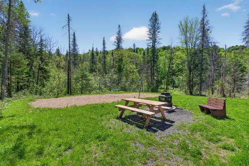 a picnic table and two benches in a field at Spa & Pool table - Le Massif in Saint Adolphe D'Howard
