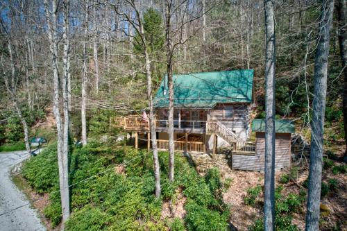 a log cabin in the woods with a green roof at Creeksong Cabin in Elk Park