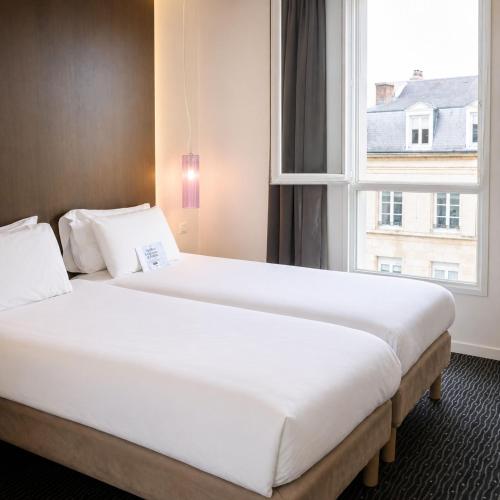 a large bed in a hotel room with a window at Kyriad Charleville Mezieres in Charleville-Mézières