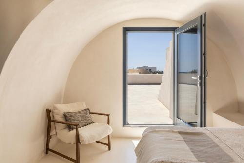 a bedroom with a bed and a chair and a window at Exomitis1 Cellar & Sea Escape in Agios Georgios Thalassiti