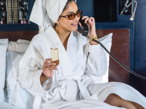 a woman talking on a phone while holding a glass of wine at Sofitel Chicago Magnificent Mile in Chicago