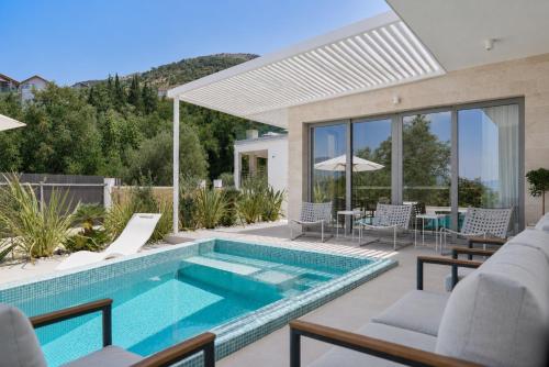 a pool in a house with chairs and a table at White Pearl Villa in Tivat