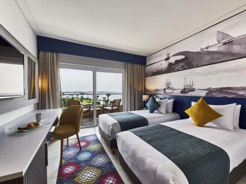 a hotel room with two beds and a desk at Mercure Ismailia Forsan Island in Ismailia