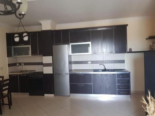 a kitchen with black cabinets and a stainless steel refrigerator at Familja Kapaj in Polisi i Vogël