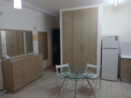 a kitchen with a glass table and two chairs and a refrigerator at Seaview Holiday Studio Peyia in Peyia