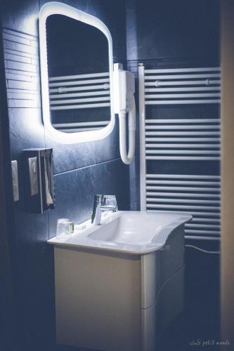 a bathroom with a white sink and a mirror at Hôtel de France in Montmarault