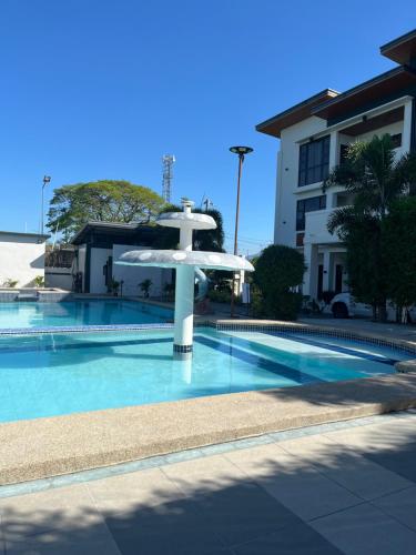 a swimming pool with a white umbrella next to a building at Reynaldos Place Corporation in Vigan