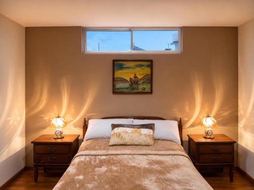 a bedroom with a bed with two night stands and two windows at Comfortable with Private Garage and Excellent Location Rb in Riobamba