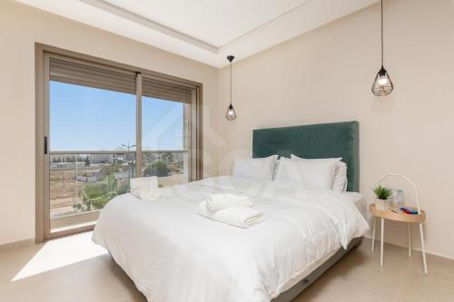a white bedroom with a large bed and a large window at Ocean & Sunset View Pool & Parking in Tamraght Ouzdar