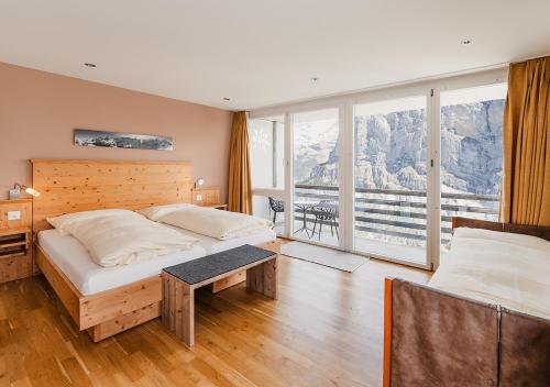 a bedroom with two beds and a large window at Hotel Edelweiss Superior in Mürren