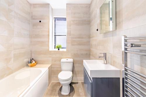 a bathroom with a toilet and a sink and a bath tub at Modern City Centre Flat in Norwich