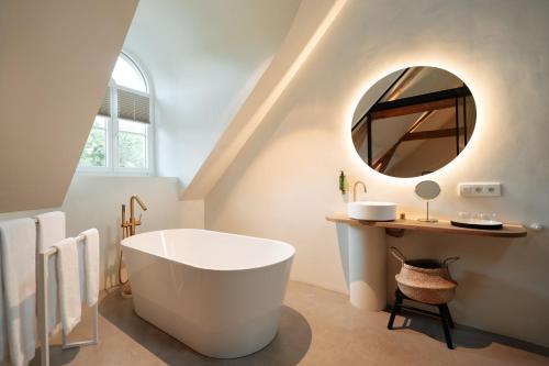 a bathroom with a large tub and a mirror at Château du Pont d'Oye in Habay-la-Neuve