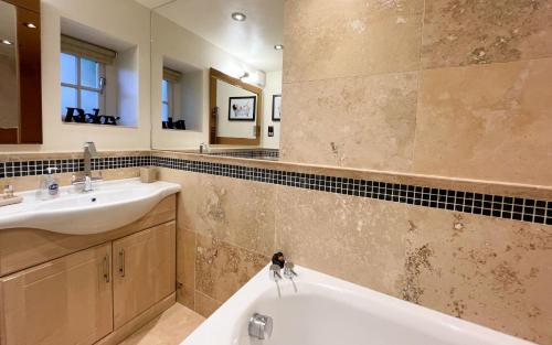 a bathroom with a tub and a sink and a mirror at Spinnaker, Whitehall in Ardeonaig