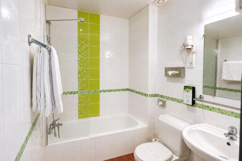 a bathroom with a tub and a toilet and a sink at Kyriad Hotel XIII Italie Gobelins in Paris