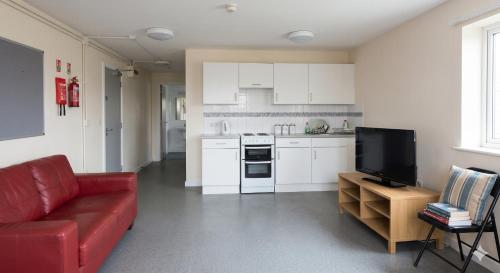 a living room with a red couch and a kitchen at Ocean Quay in Greenock