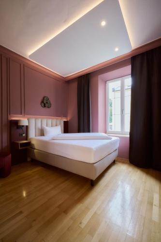ein Schlafzimmer mit einem großen Bett in einem rosa Zimmer in der Unterkunft Hotel Fletzinger in Wasserburg am Inn