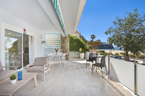 a patio with chairs and tables on a balcony at 4Brothers by 3VILLAS in Cala en Porter