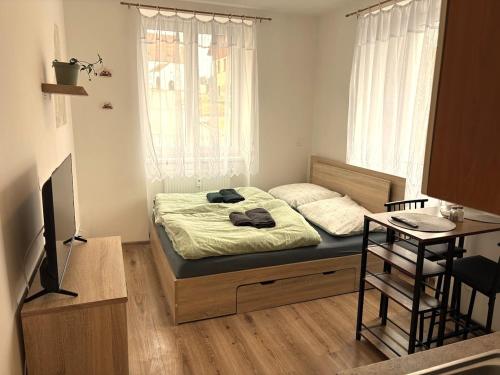 a bedroom with a bed with a window and a table at Apartmány Polná na Šumavě in Svíba