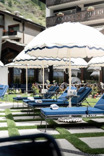 a group of blue tables with umbrellas and chairs at Le Mirabeau Resort & Spa in Zermatt