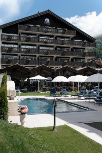 a large hotel with a pool and chairs and umbrellas at Le Mirabeau Resort & Spa in Zermatt