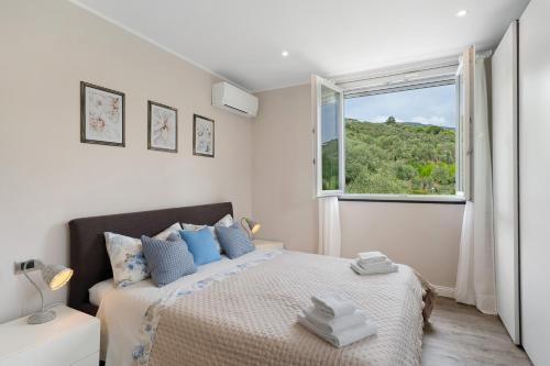 a white bedroom with a bed and a window at Casa Due Ulivi in Lavagna