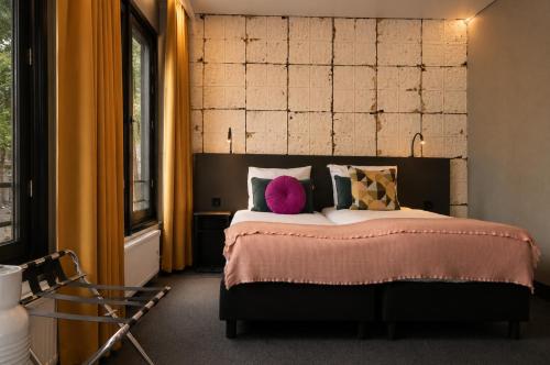 een slaapkamer met een groot bed met een roze kussen bij The Saints Sutor Hotel in Breda