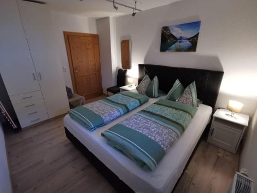 a bedroom with a large bed with blue and green pillows at Ferienwohnung Magdalena in Stumm