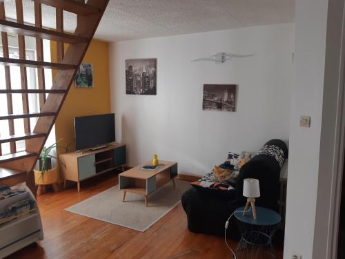 a living room with a couch and a tv at L'escapade Guingampaise in Guingamp
