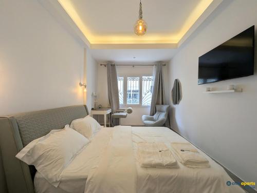 a bedroom with a large white bed with a television at Chic apart with parking and balcony in Yaoundé
