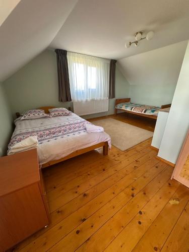 a bedroom with two beds and a wooden floor at Ela’s retreat in Dealu Mare