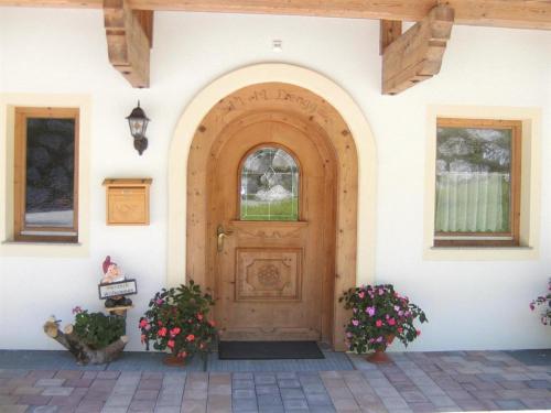 a wooden door on a white building with two plants at Ferienwohnung Dengg in Stummerberg