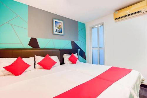 a bedroom with a large bed with red pillows at 1st Inn Hotel Klang Sentral Meru in Klang