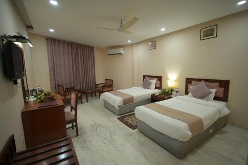 a hotel room with two beds and a television at Hotel Sujata in Bodh Gaya
