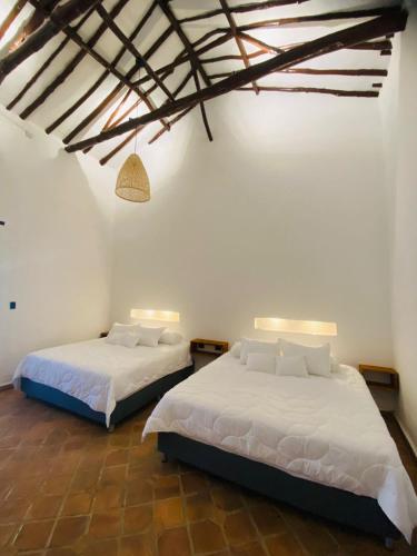 two beds in a room with white walls at Casa de ejercicios zaxue colonial in Zapatoca