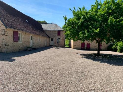 a large gravel driveway in front of a building with a tree at Gite de Foulleray n 14 in Rouez