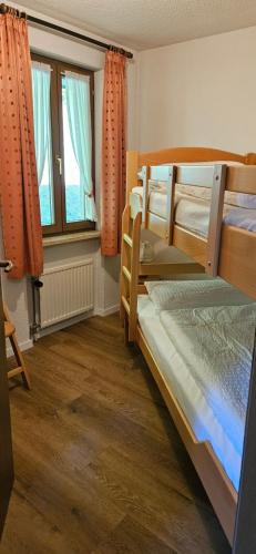 a bedroom with three bunk beds and a window at FeWo Schwarzwaldglück Todtmoos mit Sauna, Tischtennis, Fitness, Stellplätzen in Todtmoos
